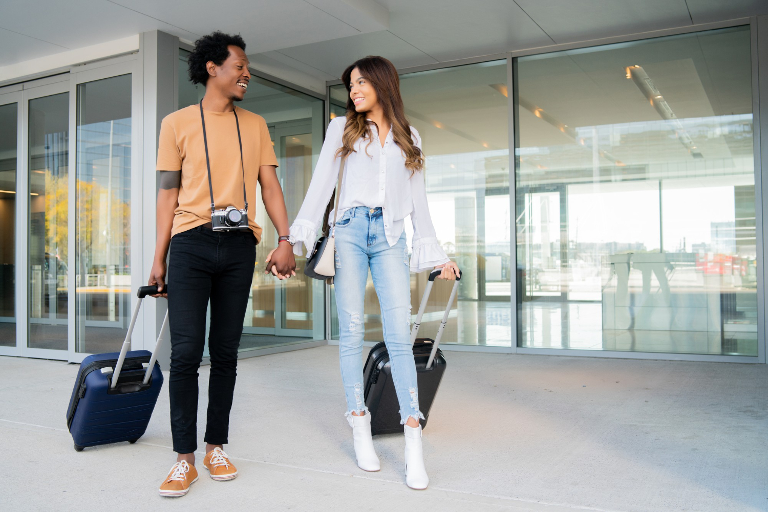 portrait-young-tourist-couple-carrying-suitcase-while-walking-outdoors-street-tourism-concept (1)